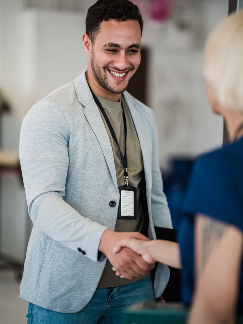 Symbolbild: Lächelnder Mann begrüßt eine Gesprächspartnerin mit Handschlag.
