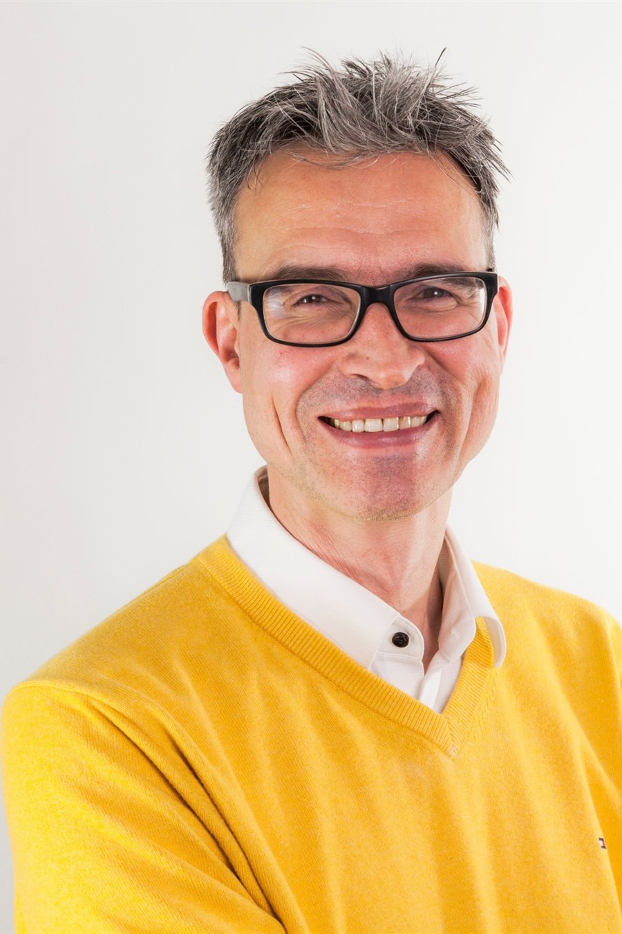 Symbolbild: Mann im gelben Pullover mit Brille.